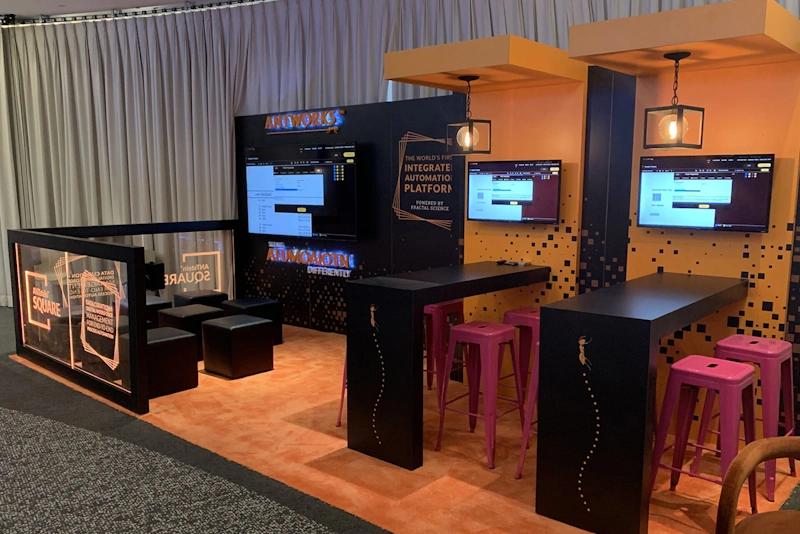 Custom trade show booth design with digital displays and seating.