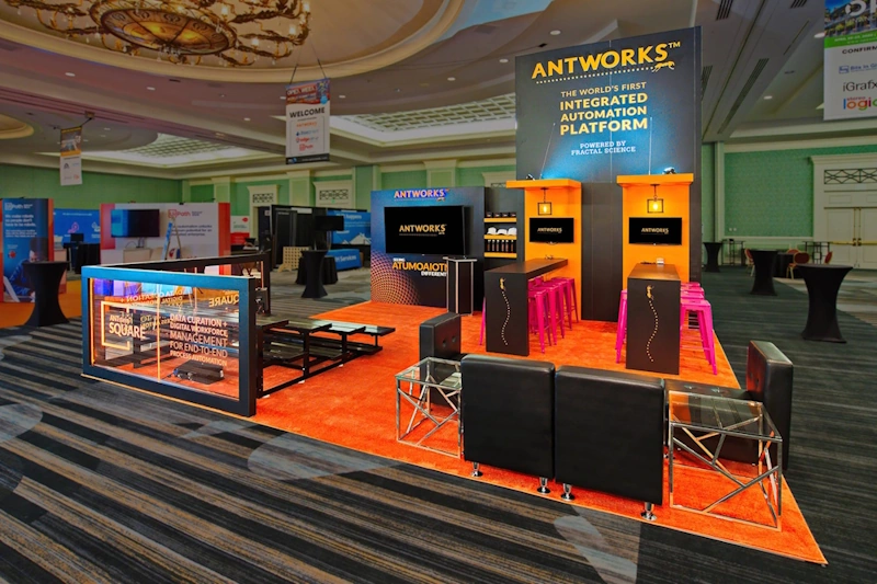 AntWorks trade show displays Florida with orange carpet, displays, and seating area.