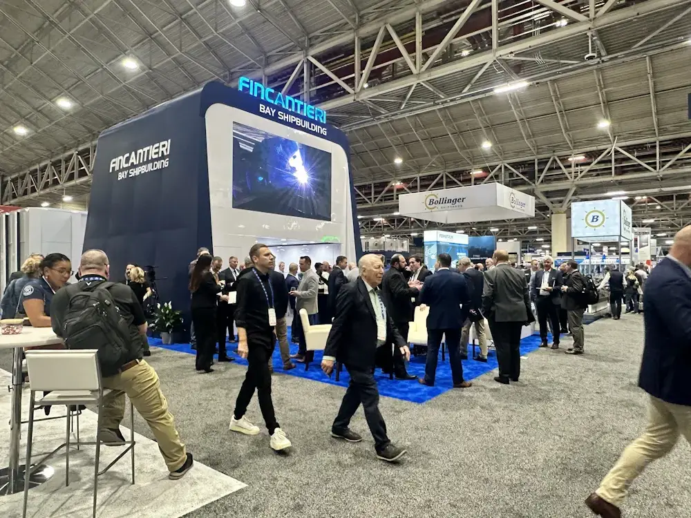 A trade show floor with a Fincantieri Bay Shipbuilding booth and many attendees