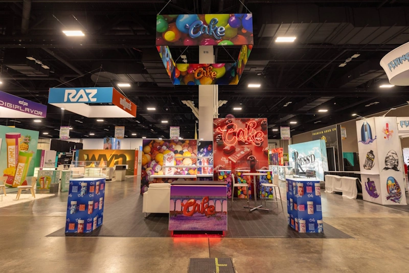 A colorful trade show displays Florida for Cake, featuring bright banners and displays surrounded by other brand booths.